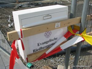 Briefkasten mit Holzlatte an Bauzaun befestigt