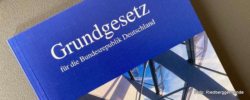 Grundgesetz der Bundesrepublik Deutschland - weiße Schrift auf blauem Grund - darunter ein Bildausschnitt Deutscher Bundestag
