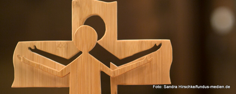 Ein Holzkreuz - 3D - mit ausgeschnittener Jesus-Figur davor - mit ausgebreiteten Armen