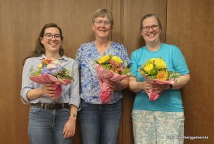 Gruppenfoto - drei lachende Frauen mit Blumensträußen in den Händen.